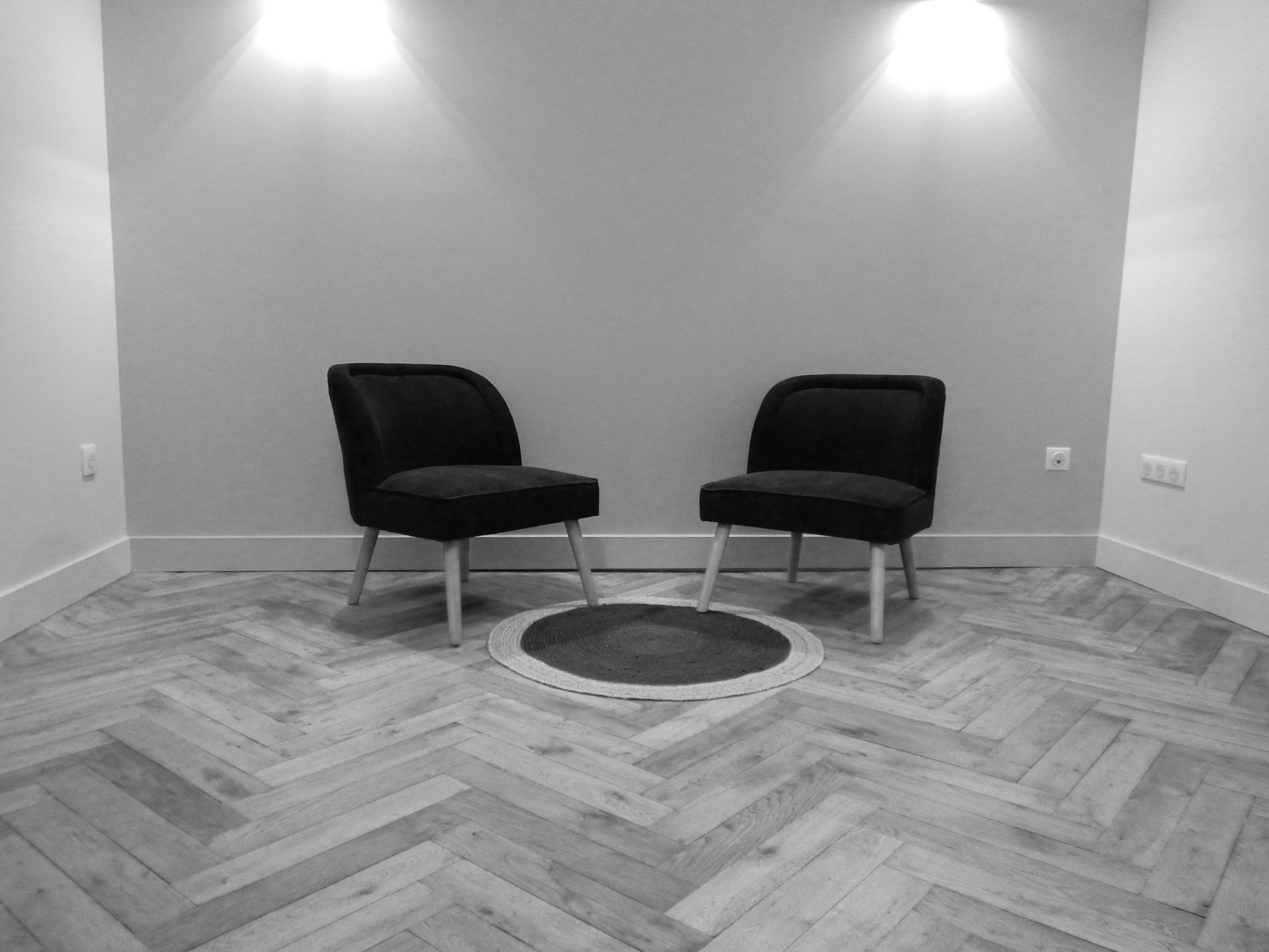 Photo représentant l'espace d'accueil pour vous recevoir, 2 sieges côte à côté afin de discuter dans une pièce vide et sans interférence extérieure. Photo en noir et blanc.